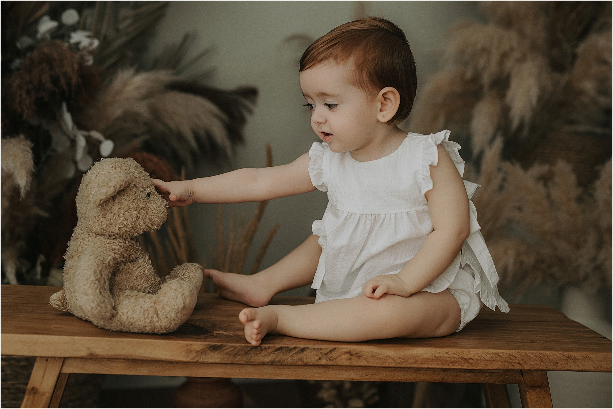 Bebé de un año jugando con un peluche durante su sesión de fotos