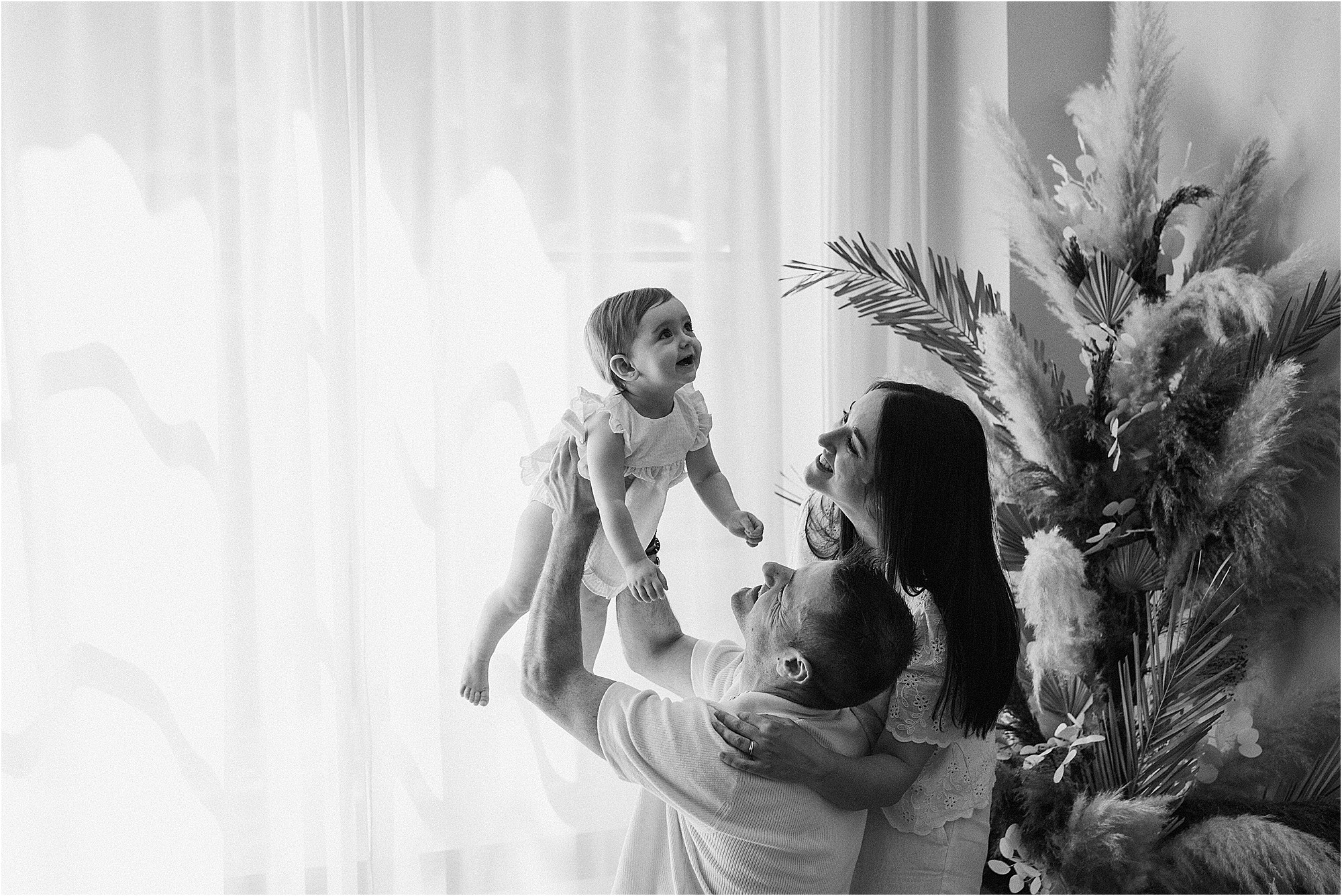 Familia jugando con su bebé de un año durante una sesión de fotos