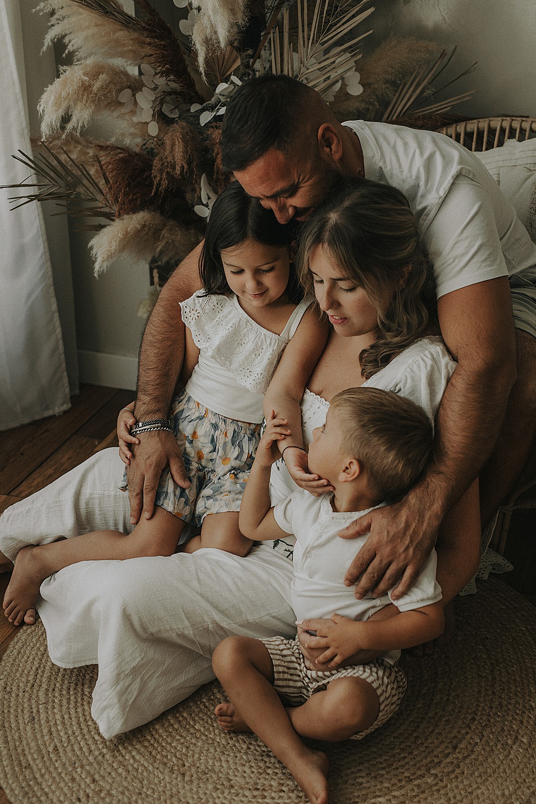 Padres abrazando a sus tres hijos durante una sesión familiar natural