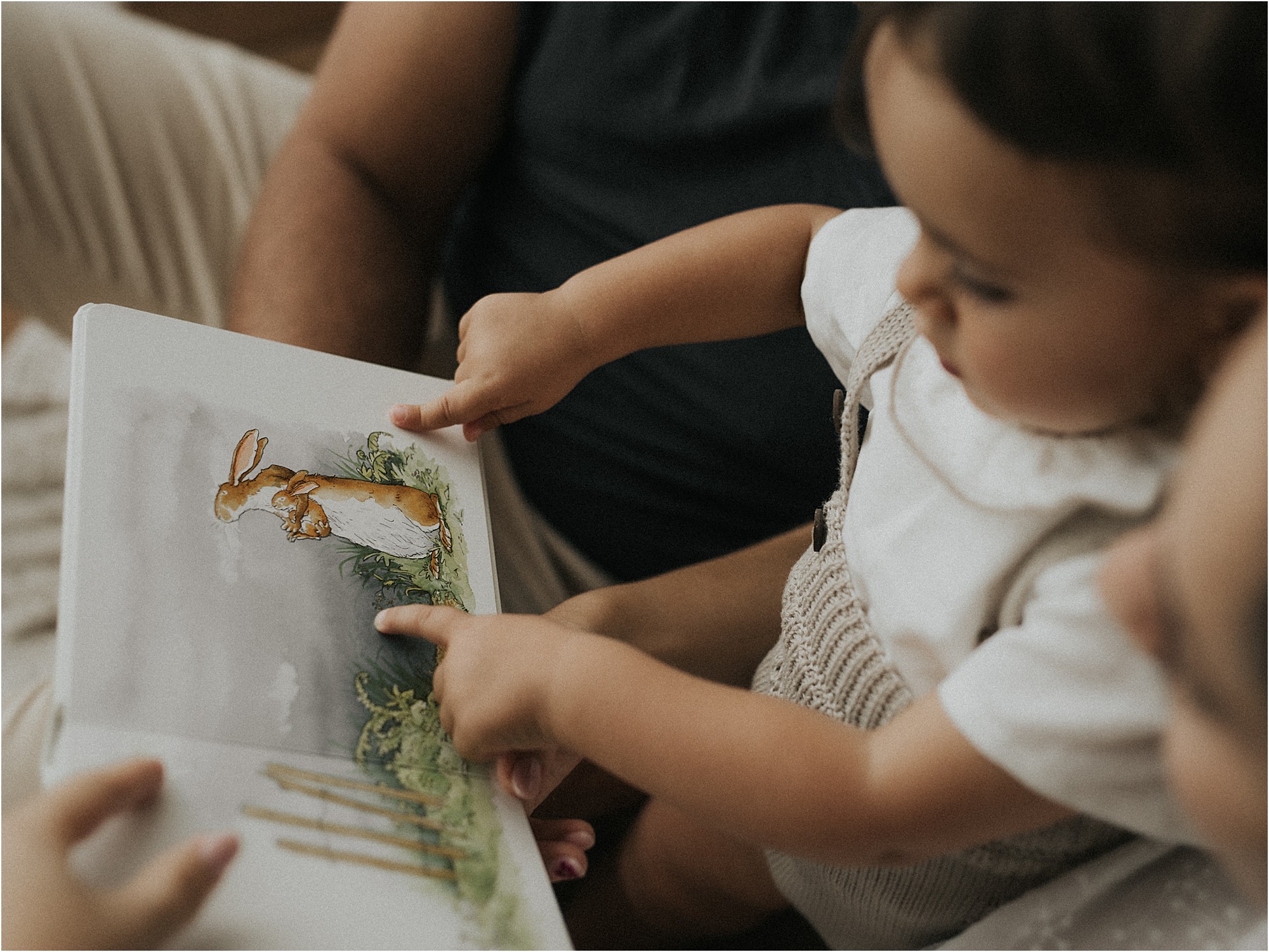 Niña pequeña mirando un cuento ilustrado junto a sus padres