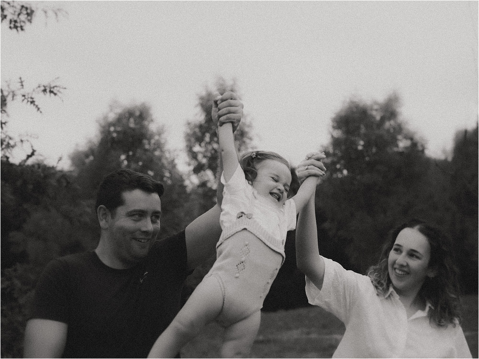 Padres jugando y levantando a su hija en el aire