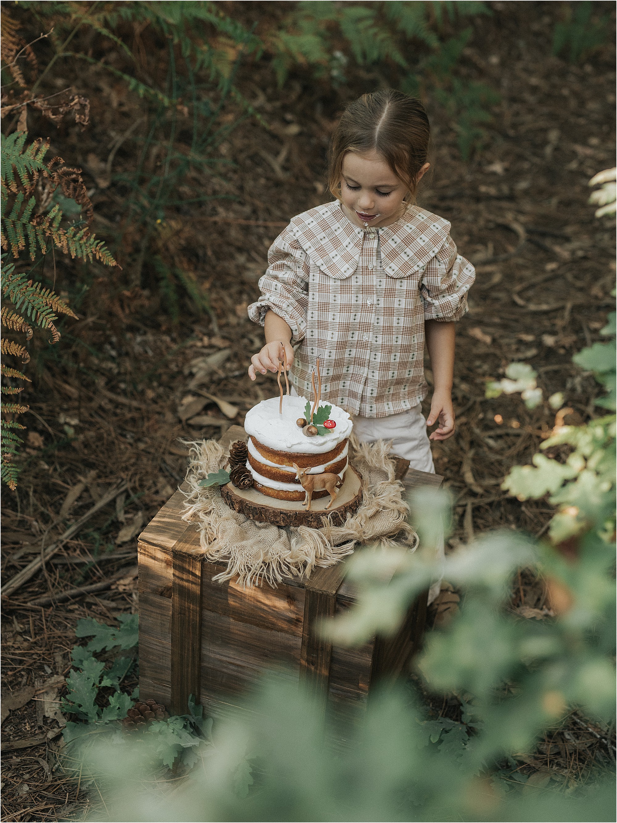 Aria con vestido de cuadros junto a su tarta en el bosque